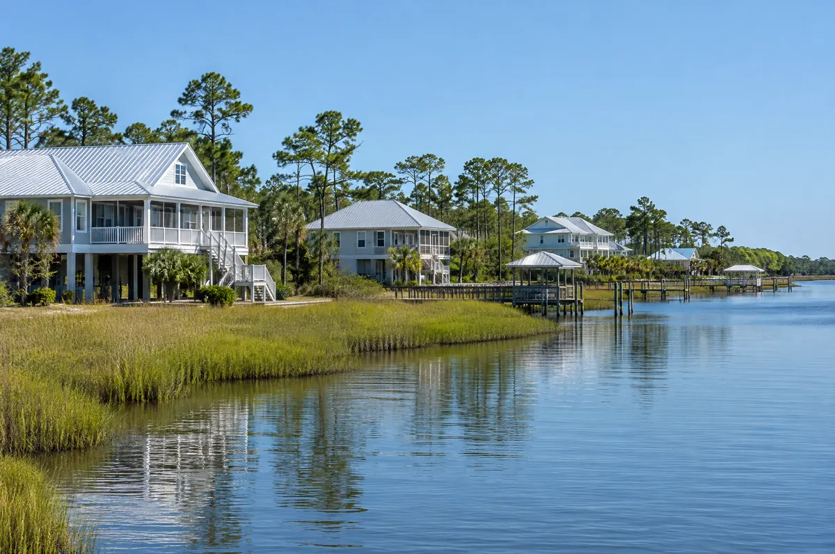 Homes on raised foundations beside a calm bay