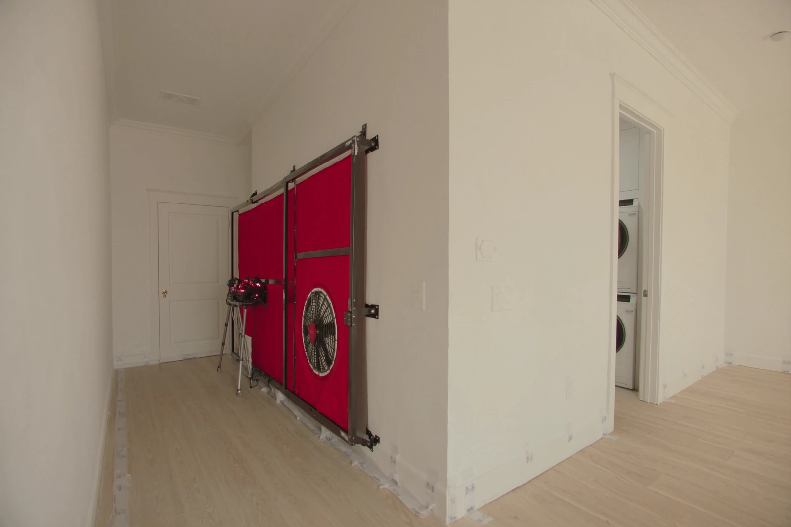 Blower door fan set up in a hallway doorway of a new home