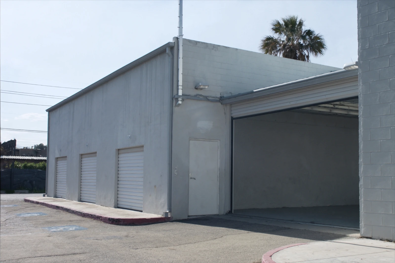 Commercial building with a raised loading bay door and a row of roll-up doors