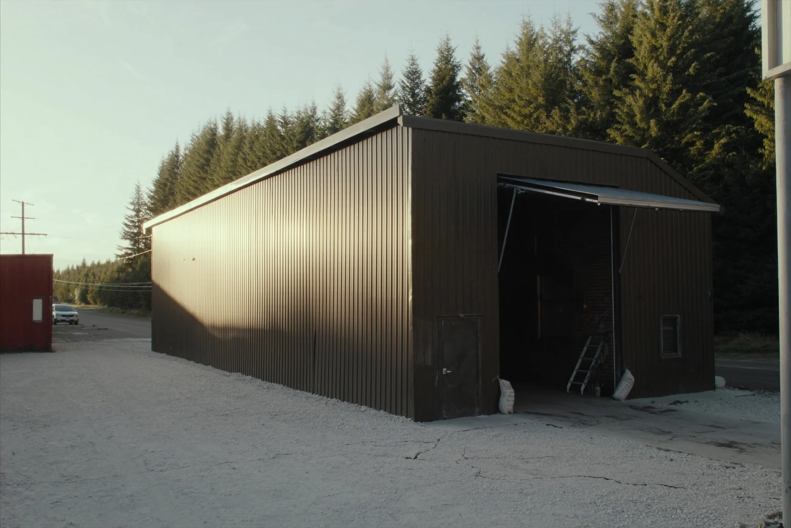 Metal shop building with a steel overhead door raised on a gravel lot