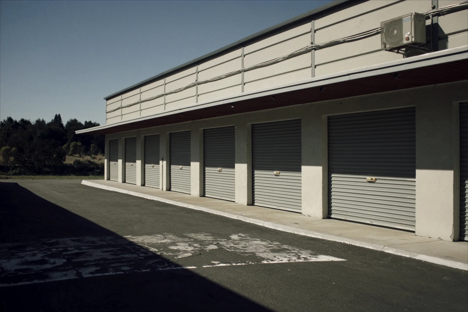 Row of gray roll-up doors along a long low commercial building