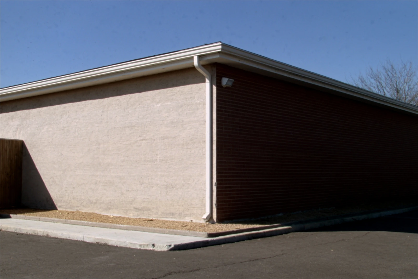 Small brick office building with white gutters and a downspout at the corner