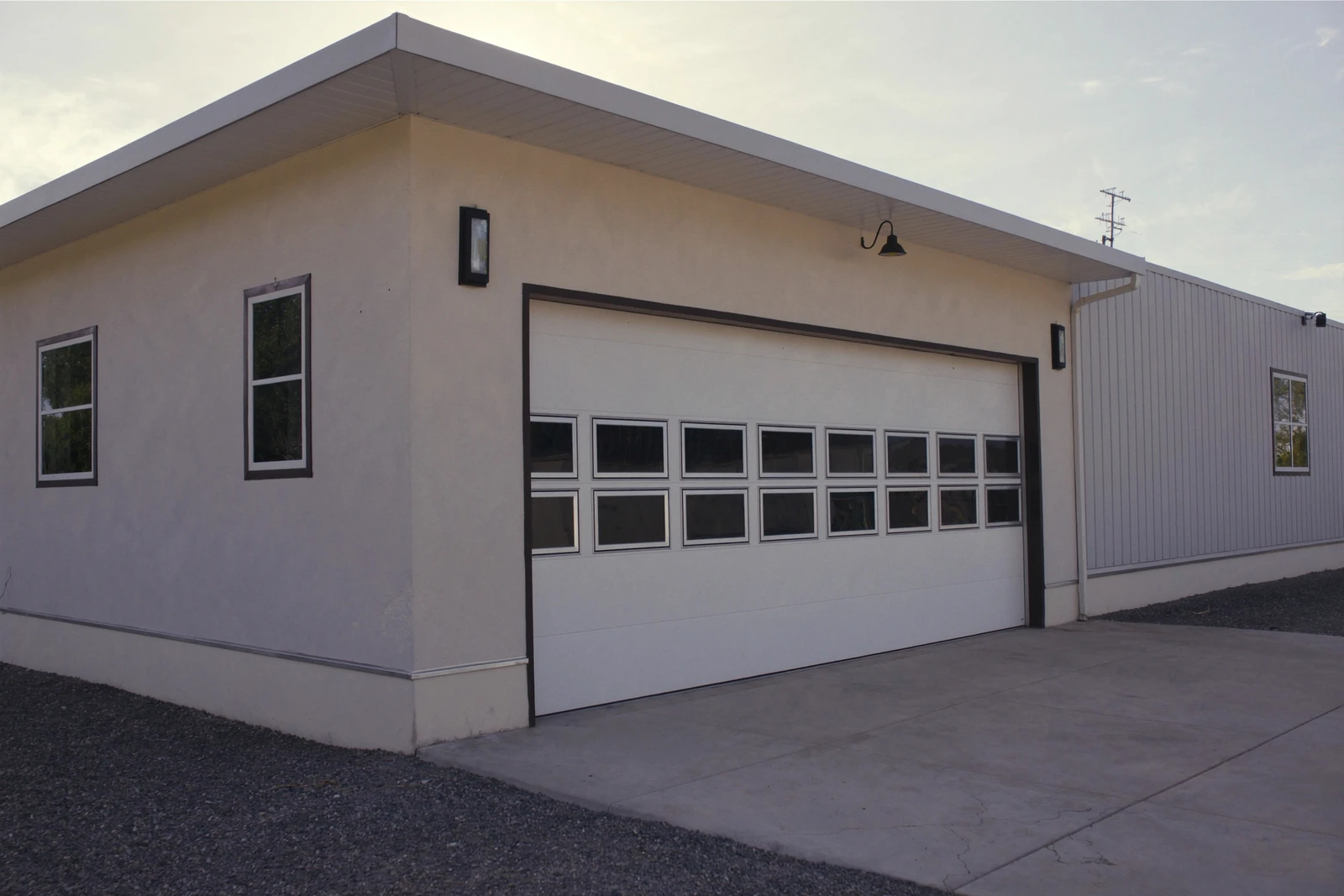 Large white garage door with a row of window panels on a stucco building