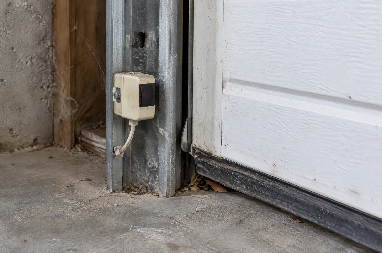 Garage door safety sensor mounted low on the door track