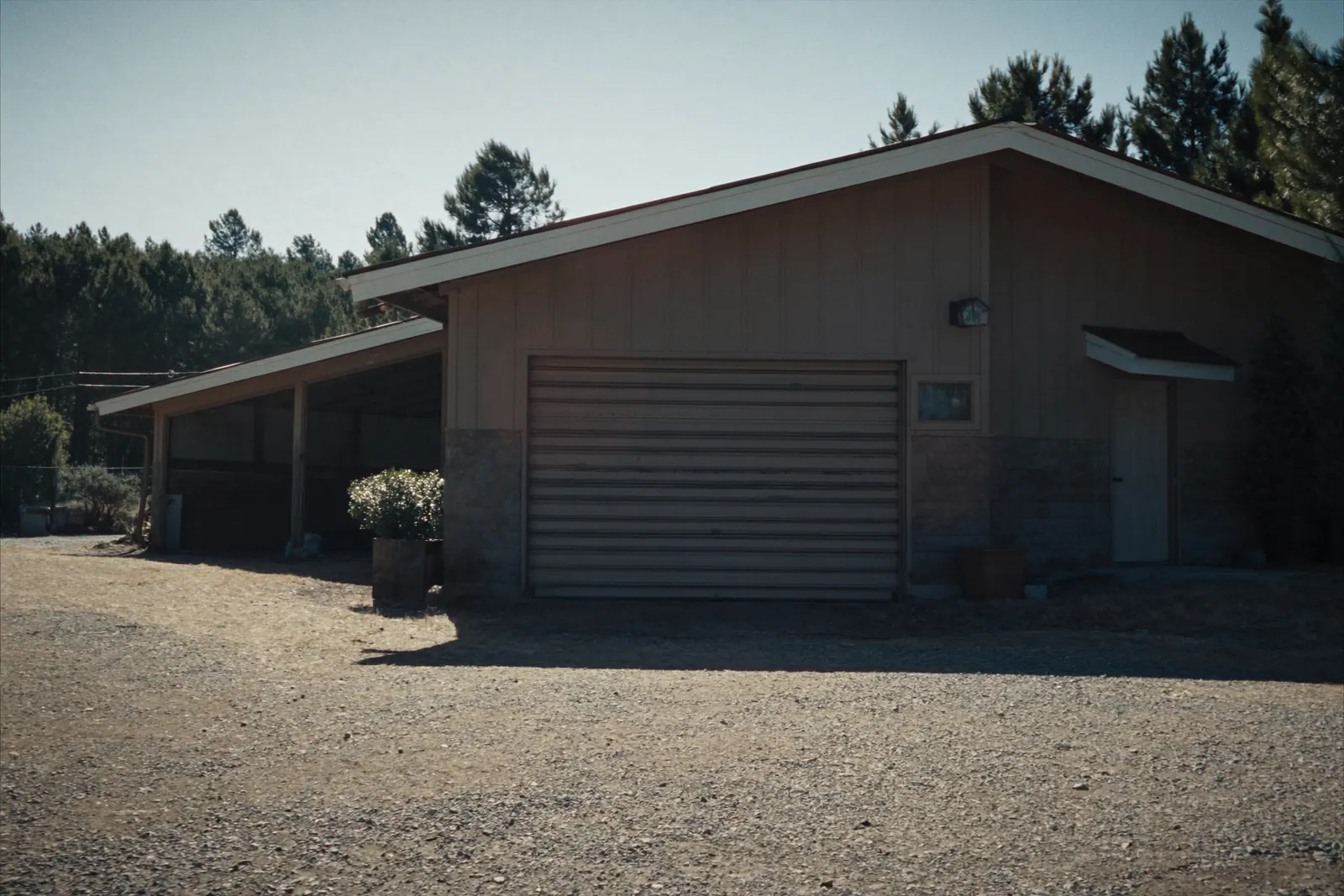 Detached workshop with a tan steel rolling door and a side entry door