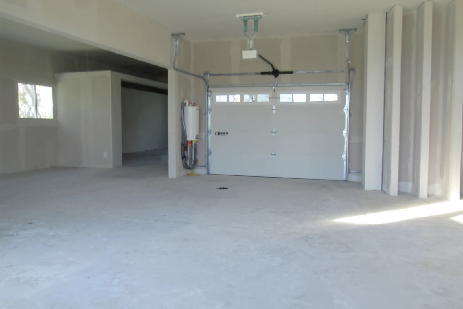 Empty garage of a newly built house with a white door and a water heater