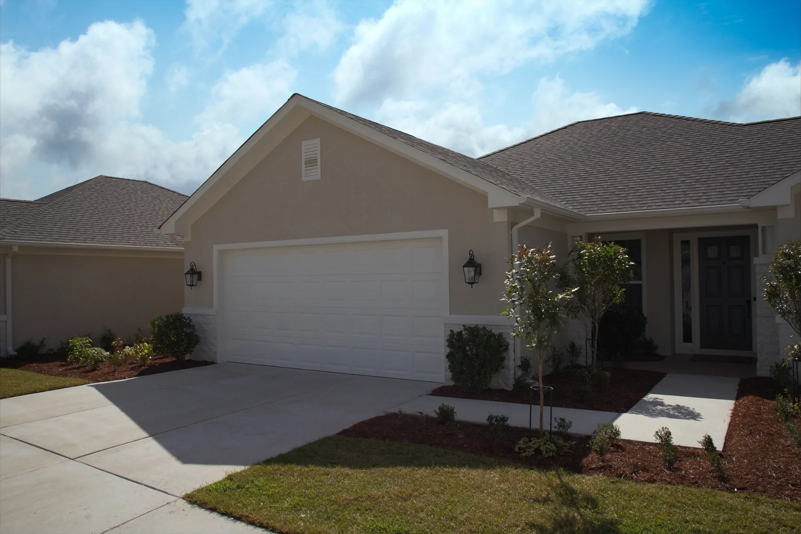 Newly built stucco home with a white garage door and a new concrete driveway
