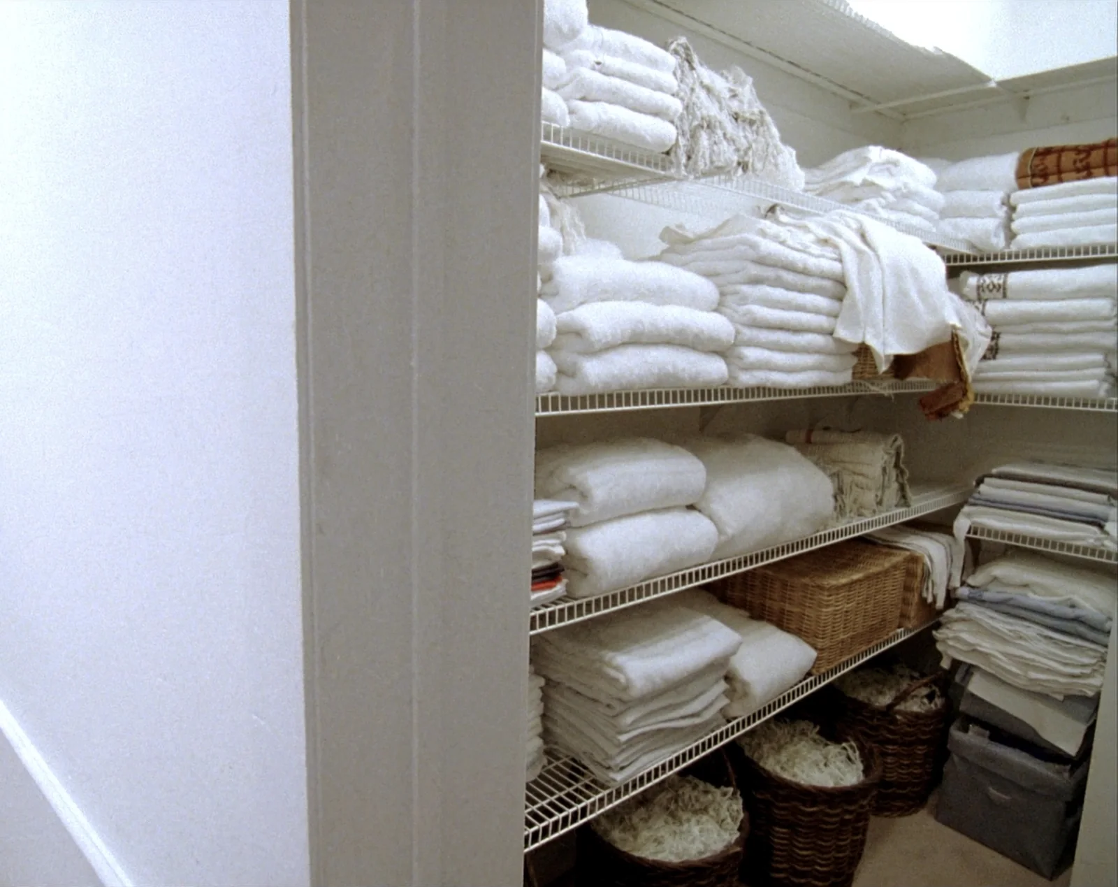 Linen closet with wire shelves holding folded towels and sheets