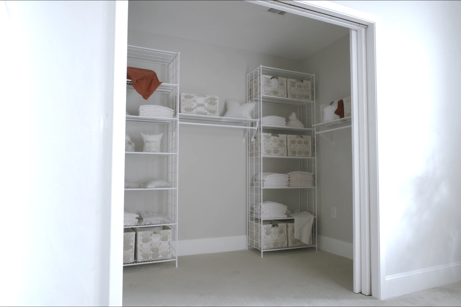 Closet with white wire shelving holding folded linens and baskets