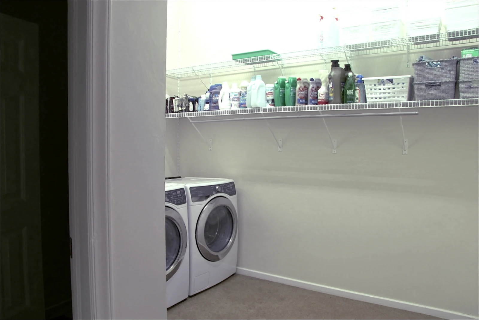 Wire shelf above a washer and dryer holding laundry supplies