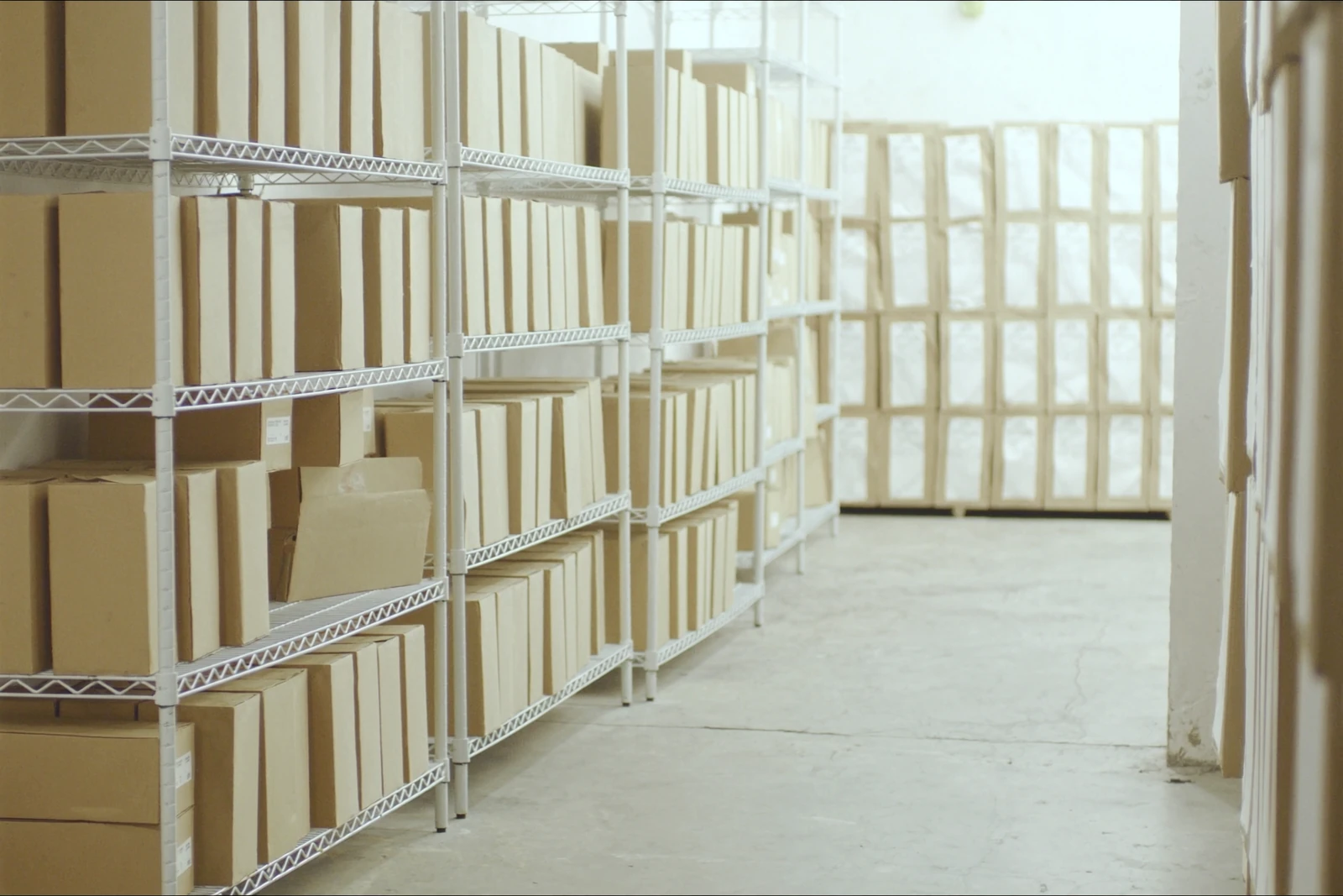 Stockroom with rows of white wire shelving holding boxes